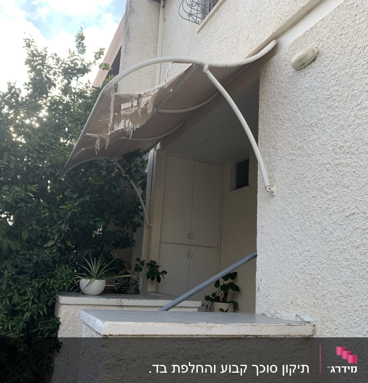 סוכך מתכת עם בד קרוע על קיר חיצוני